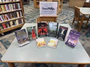 A display of the 2024 Joan Phillips Memorial Library Fund featuring 8 adult fiction titles for the Solomonson Branch.